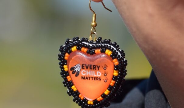 Heather George wears a pair of earrings with the slogan "Every Child Matters" while marching with Mohawk Institute survivors and their families for access to Anglican Church records. Photo by Celia Clarke, NCPR