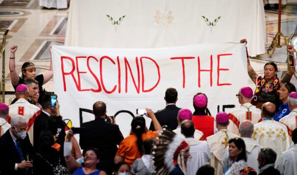 Protesters hold a banner during a Mass with Pope Francis at the National Shrine of Saint Anne de Beaupre, on July 28, 2022, in Saint Anne de Beaupre, Quebec, Canada, calling for rescission of the Doctrine of Discovery, which allows Christian settlers to "discover" lands that are home to non-Christian people. The doctrine, which originated with a papal bull in the 1400s, was incorporated into U.S. law with the Johnson v. M'Intosh ruling by the U.S. Supreme Court in 1823.  The Vatican renounced the doctrine with a surprise announcement on March 30, 2023, but that will not change U.S. case law. (AP Photo/John Locher)