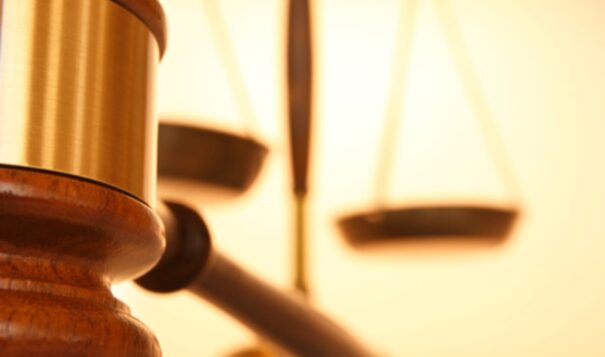 Close up of gavel with justice scale in background - stock photo.