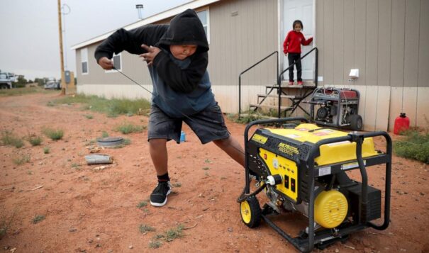 Jayden Long starts the generator behind his Kaibeto home on the Navajo Reservation in Arizona, May 8, 2019, so that he can charge his cell phone inside the family home. The U.S. Interior Department on Tuesday, Aug. 15, 2023, unveiled a new program to bring electricity to more homes in Native American communities as the Biden administration looks to funnel more money toward climate and renewable energy projects. (AP Photo, Jake Bacon)