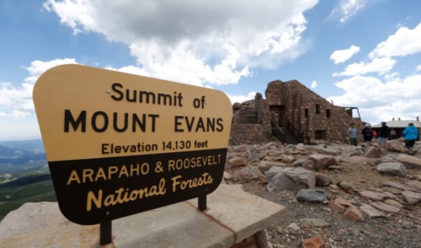 Visitors pass the sign on the summit of Mount Evans near Idaho Springs, Colo., on July 15, 2016. A Colorado state panel changed the mountain’s name on Friday, Sept. 15, 2023, to Mount Blue Sky. (AP Photo/David Zalubowski, File)
