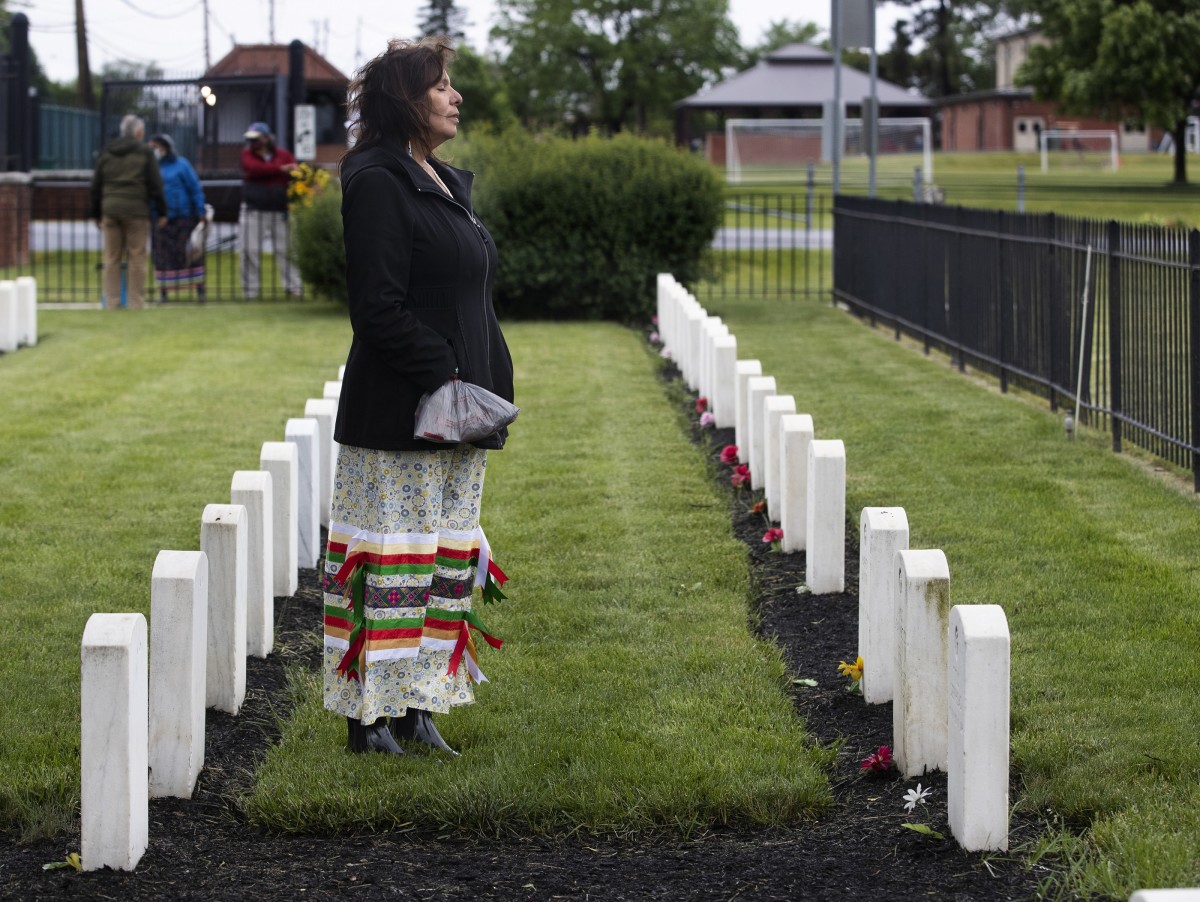 ONE TIME USE ONLY with story by Charles Fox on return of moccasins: Kelley Bova, of Pennsylvania, pays her first visit to the Indian Cemetery on May 29, 2021, at the site where the Carlisle Indian Industrial School operated from 1879-1918.  Bova was taken from her family as an infant and adopted out at three months old to a White Pennsylvania family. She later reconnected with her birth family and is now a member of the Sisseton Wahpeton Oyate. (Photo by Charles Fox, courtesy of The Philadelphia Inquirer)