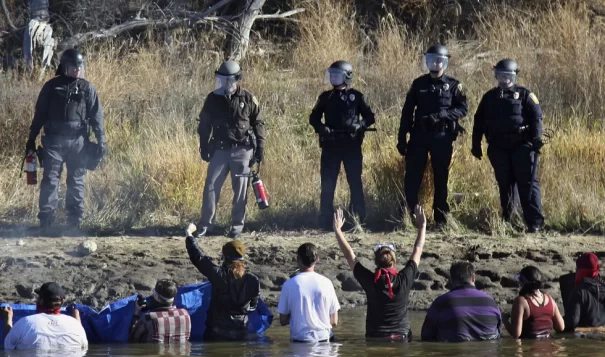Protestors demonstrating against the expansion of the Dakota Access Pipeline wade in cold creek waters confronting local police, near Cannon Ball, N.D., Nov. 2, 2016.  (John L. Mone/AP)